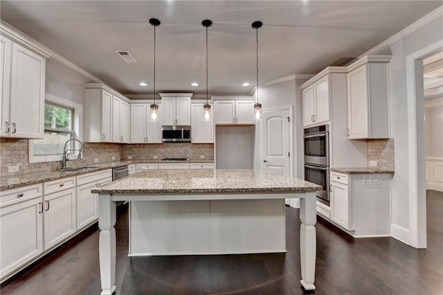 kitchen featuring a kitchen island, appliances with stainless steel finishes, a sink, light stone counters, and dark wood-type flooring