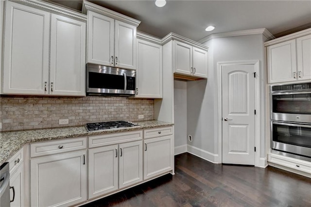 kitchen featuring appliances with stainless steel finishes, dark wood finished floors, white cabinetry, baseboards, and tasteful backsplash