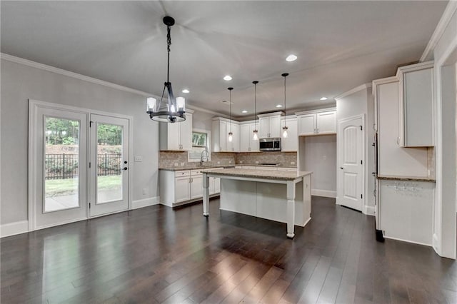 kitchen featuring backsplash, light stone counters, stainless steel microwave, dark wood-style floors, and a chandelier