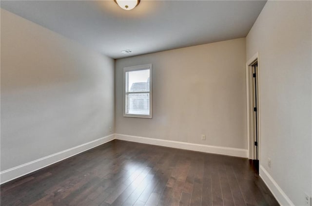 spare room featuring baseboards, visible vents, and dark wood-type flooring