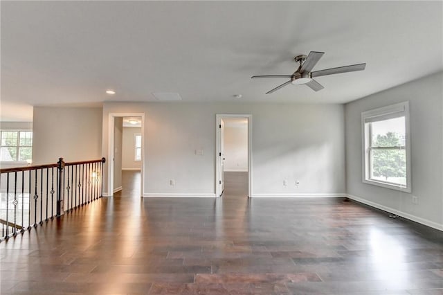 spare room featuring dark wood-type flooring, baseboards, ceiling fan, and a healthy amount of sunlight