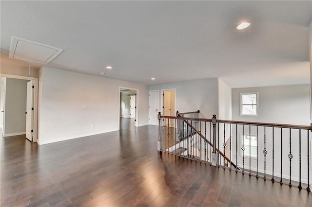 empty room featuring recessed lighting, baseboards, attic access, and dark wood-type flooring