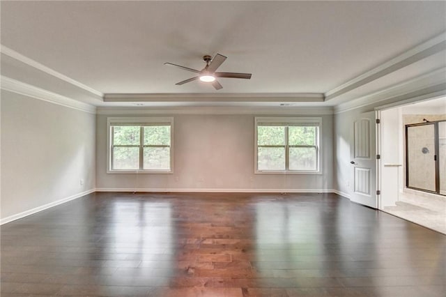 empty room with crown molding, a raised ceiling, and dark wood-style floors