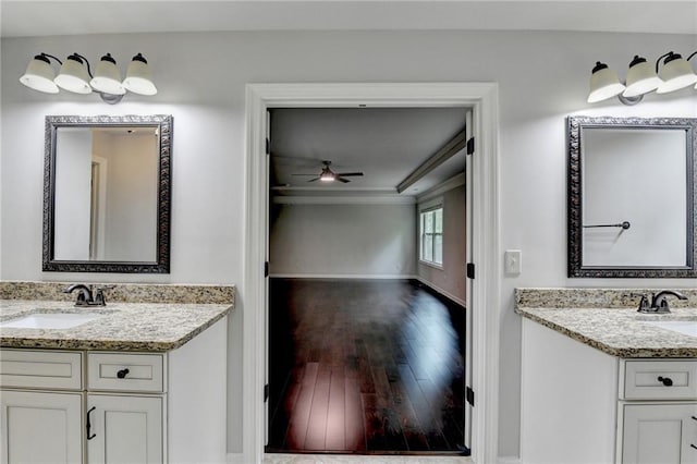 bathroom featuring a ceiling fan, two vanities, a sink, baseboards, and hardwood / wood-style floors