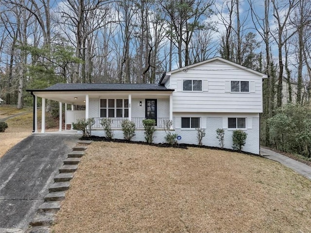 split level home featuring aphalt driveway, an attached carport, covered porch, and brick siding