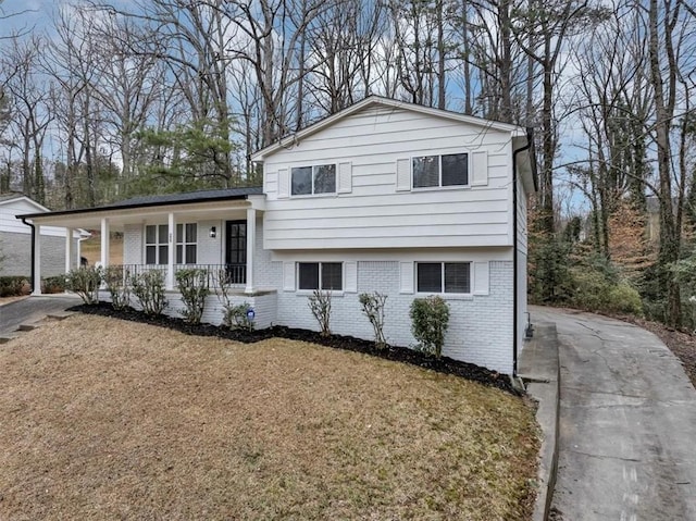 split level home with driveway, a front yard, a porch, and brick siding