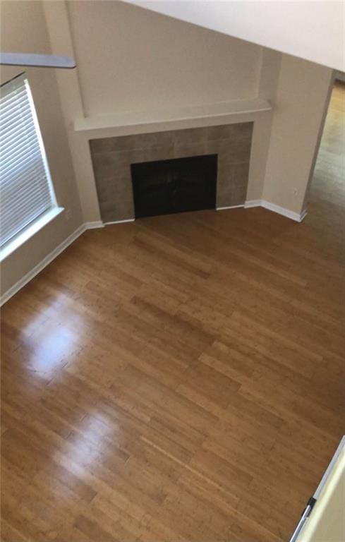 unfurnished living room featuring a tiled fireplace and wood-type flooring