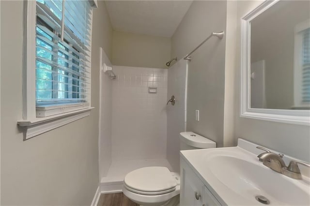 bathroom featuring toilet, a tile shower, and vanity