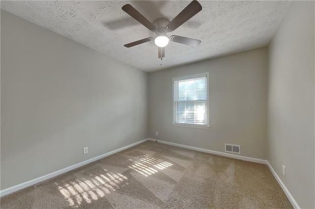 carpeted empty room with ceiling fan and a textured ceiling