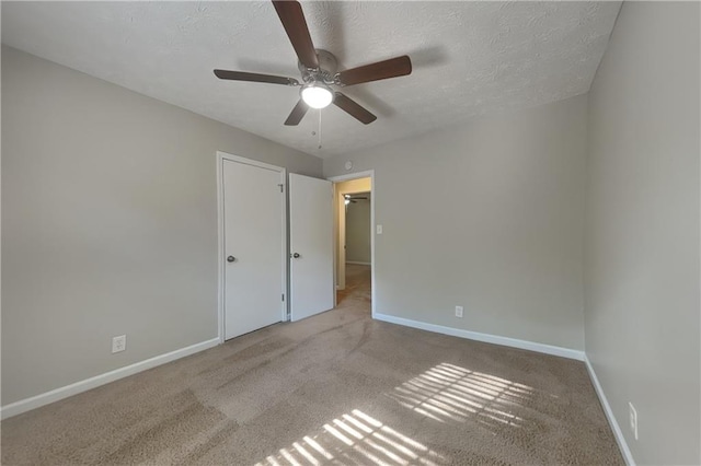 unfurnished bedroom with a textured ceiling, light colored carpet, and ceiling fan