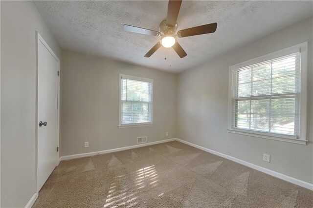 carpeted spare room featuring ceiling fan and a textured ceiling