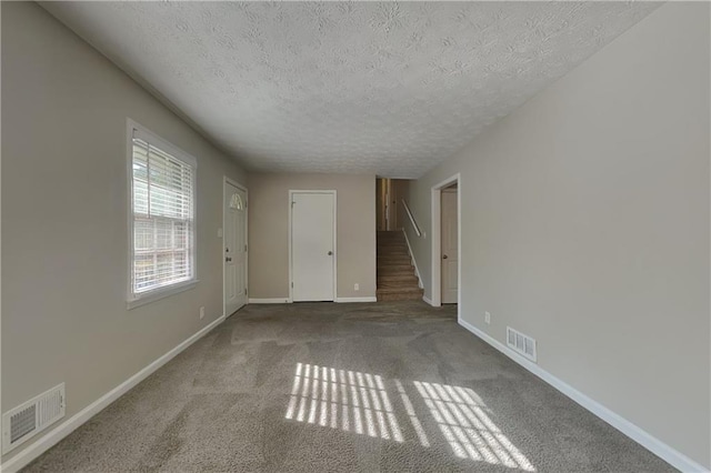 carpeted spare room with a textured ceiling