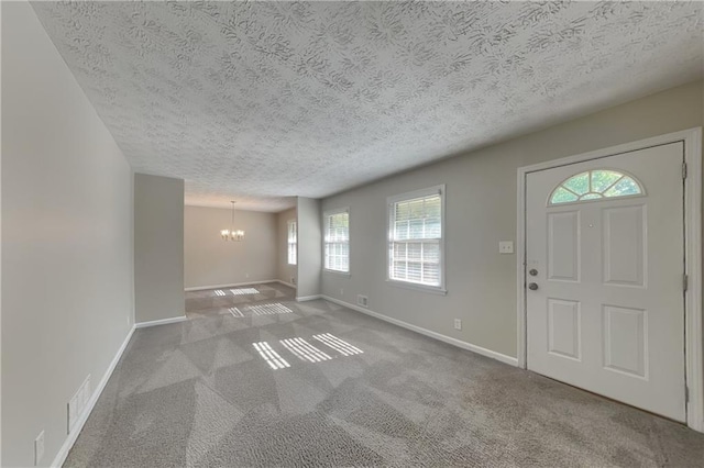 foyer featuring carpet, a textured ceiling, and a notable chandelier