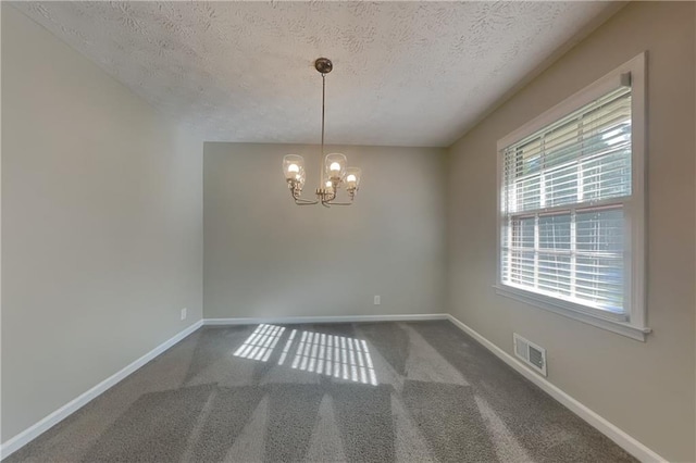 empty room with carpet, a textured ceiling, and an inviting chandelier