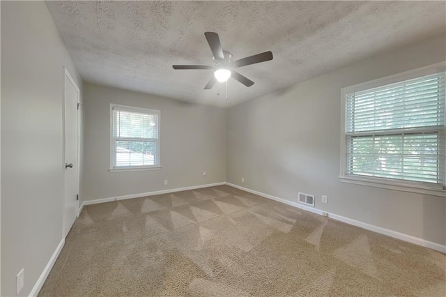 unfurnished room featuring ceiling fan, light colored carpet, and a textured ceiling