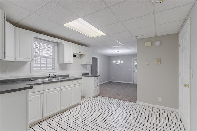 260 Pleasant Grove Cir, Mcdonough, GA 30252 - kitchen with a drop ceiling, dark countertops, a sink, white cabinetry, and a chandelier