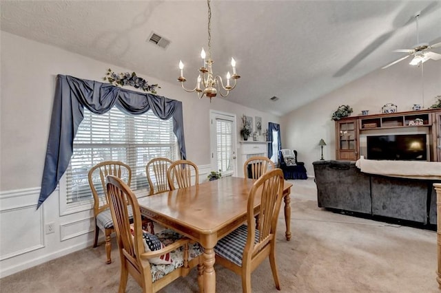 dining area with ceiling fan with notable chandelier, light colored carpet, and vaulted ceiling