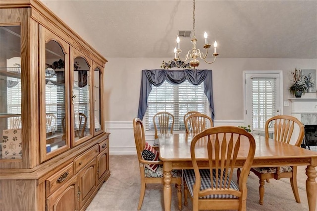 carpeted dining room featuring a high end fireplace and a chandelier