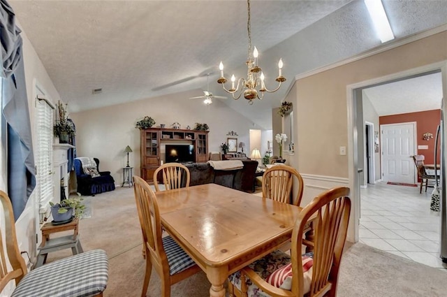 dining area with a textured ceiling, ceiling fan with notable chandelier, lofted ceiling, and light tile patterned flooring