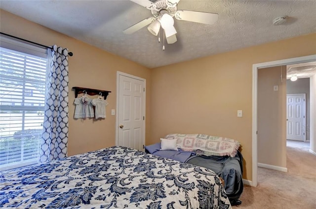 bedroom with ceiling fan, light colored carpet, and a textured ceiling