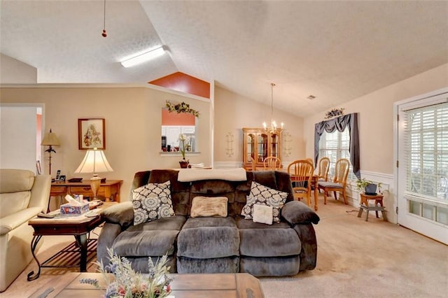 living room with light carpet, a chandelier, and vaulted ceiling