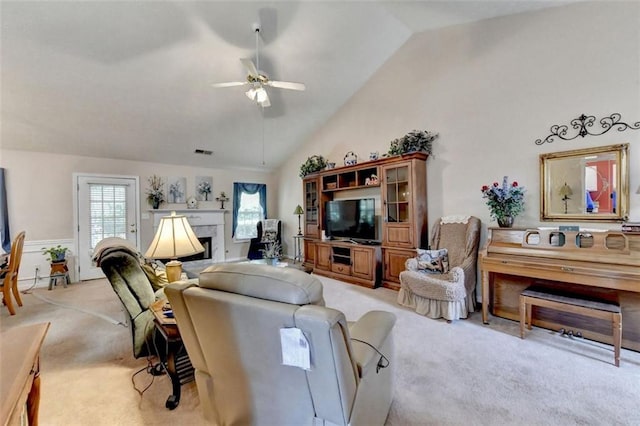 carpeted living room with ceiling fan and vaulted ceiling