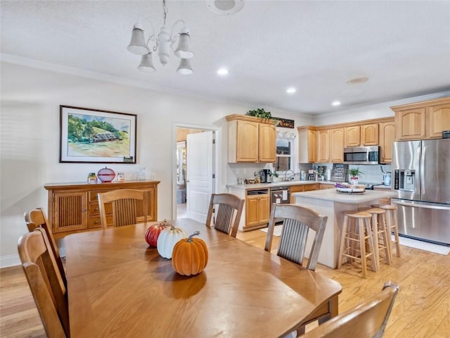 dining space featuring sink, ornamental molding, light hardwood / wood-style flooring, and a chandelier