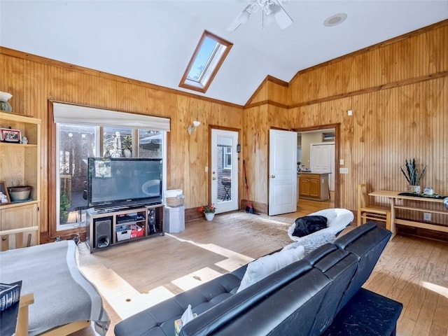 living room featuring vaulted ceiling with skylight, ceiling fan, and wood-type flooring