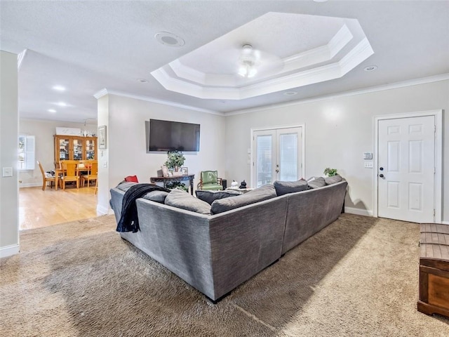 living room with french doors, carpet floors, a tray ceiling, and ornamental molding