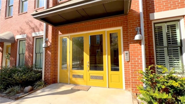 view of exterior entry featuring brick siding and french doors
