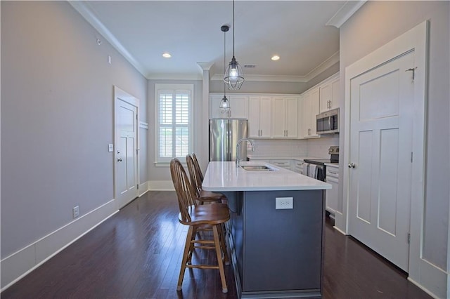 kitchen with a sink, ornamental molding, stainless steel appliances, white cabinetry, and dark wood-type flooring