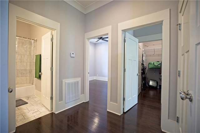 hall with baseboards, visible vents, and wood finished floors