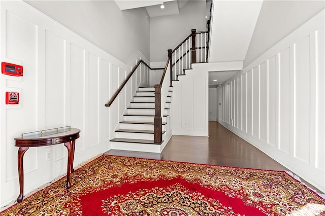 entryway featuring wood finished floors, a decorative wall, and stairway