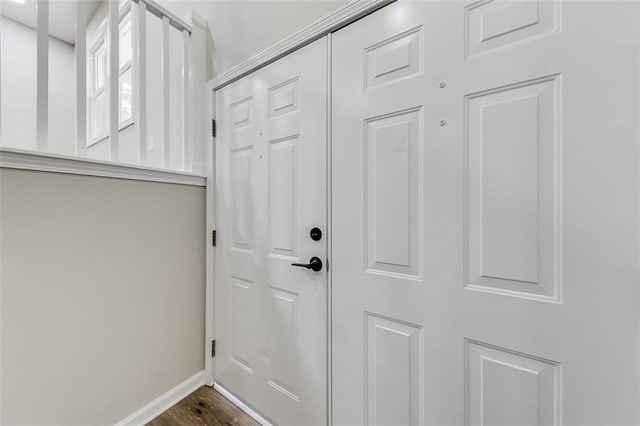 doorway featuring dark wood-style floors and baseboards