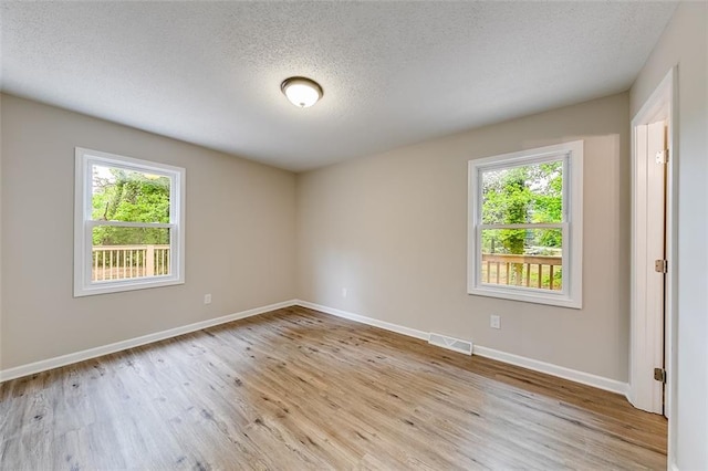 unfurnished room with visible vents, plenty of natural light, and light wood-style floors