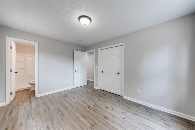 unfurnished bedroom with a closet, a textured ceiling, wood finished floors, and baseboards