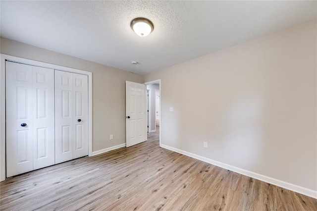 unfurnished bedroom with baseboards, a closet, and light wood finished floors