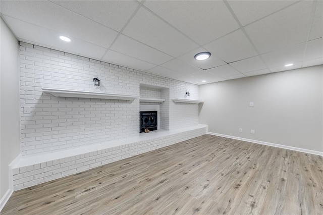 unfurnished living room with wood finished floors, a paneled ceiling, recessed lighting, and baseboards