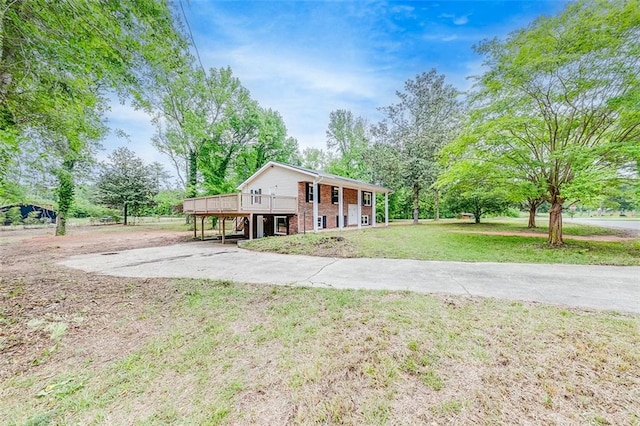view of front of property with a deck, a front yard, and brick siding