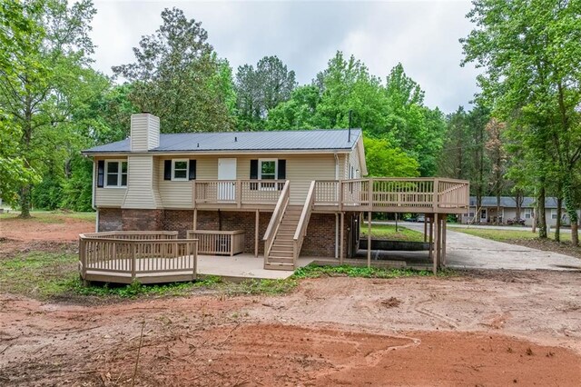 rear view of property with stairway, a chimney, and a wooden deck