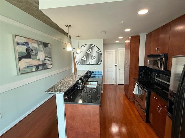 860 Peachtree St NE Unit 1411, Atlanta, GA 30308 - kitchen with appliances with stainless steel finishes, dark wood-style flooring, dark stone countertops, backsplash, and decorative light fixtures