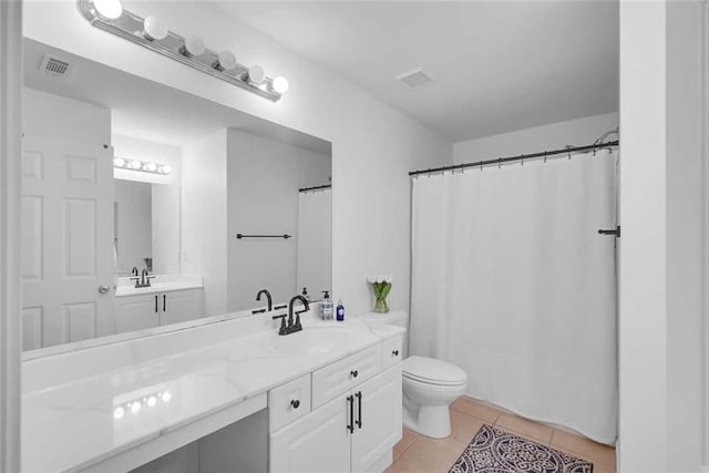 bathroom with toilet, vanity, and tile patterned floors