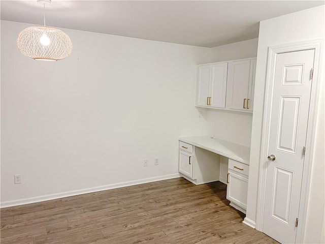 unfurnished office featuring light wood-type flooring and built in desk