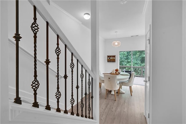 stairway featuring hardwood / wood-style flooring, a chandelier, and ornamental molding