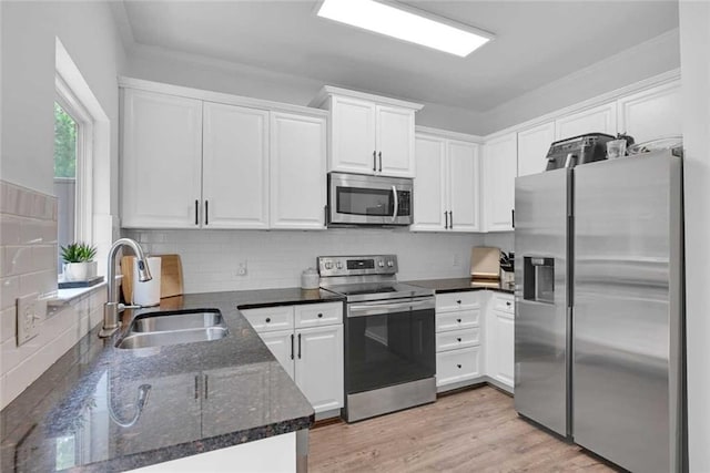 kitchen with white cabinets, sink, light hardwood / wood-style flooring, and appliances with stainless steel finishes