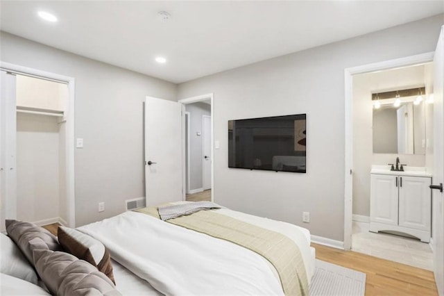 bedroom featuring baseboards, recessed lighting, connected bathroom, and light wood-style floors