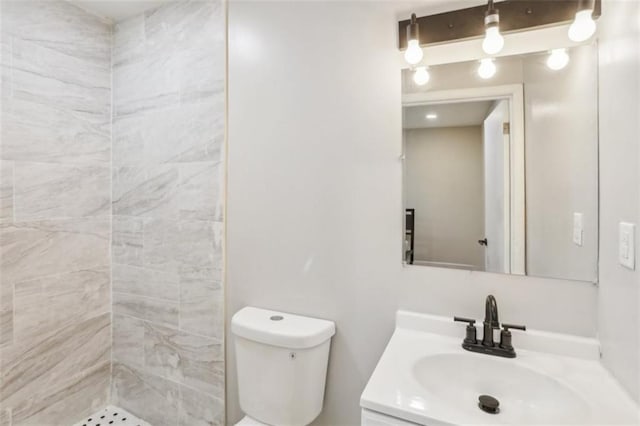 bathroom featuring tiled shower, vanity, and toilet