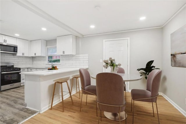 dining room with recessed lighting, crown molding, light wood-style flooring, and baseboards