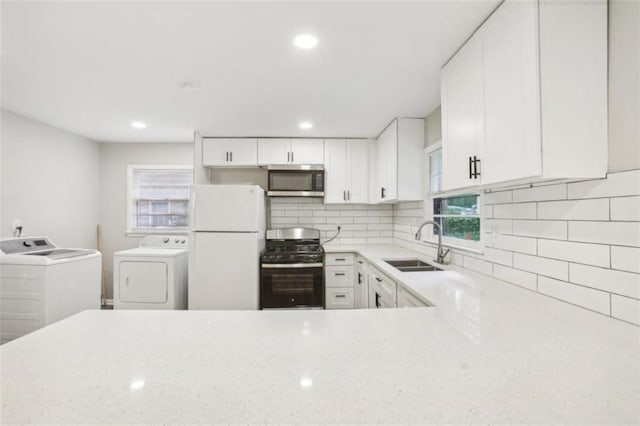 kitchen featuring decorative backsplash, appliances with stainless steel finishes, a sink, light stone countertops, and independent washer and dryer