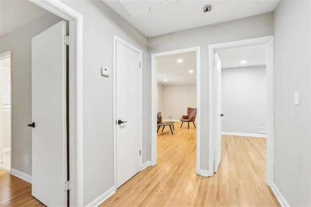 corridor featuring light wood finished floors, attic access, baseboards, and recessed lighting